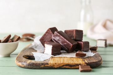 Board with tasty bird's milk candies on color wooden table