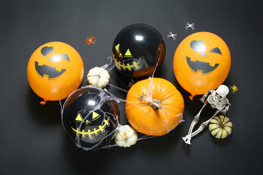 Composition with Halloween balloons, pumpkins and web on dark background