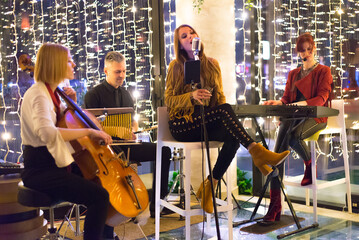 Musical band playing music on the small concert stage at night in restaurant - obrazy, fototapety, plakaty