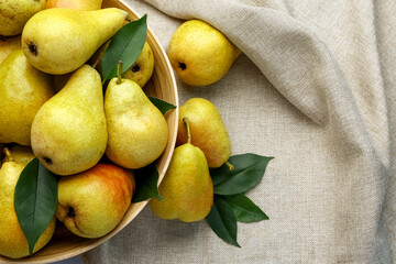 Bowl with ripe pears on fabric background, closeup