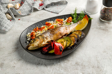 Fried sea bass with grilled vegetables on grey table - 536860733