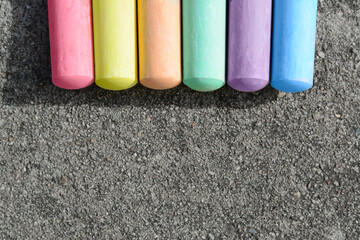 Colorful chalk sticks on asphalt, flat lay. Space for text