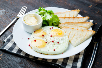 Fried eggs with toasts on dark wooden table