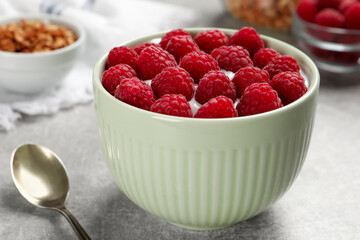 Bowl with delicious yogurt and raspberries on grey table, closeup