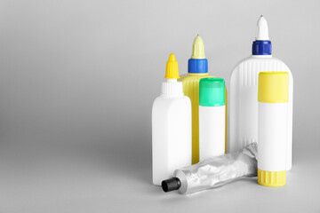 Different bottles of glue on grey background, space for text