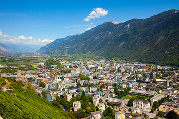 Fototapeta na wymiar Summer view from drone of Martigny town in green valley on banks of Rhone river surrounded by Alps, Switzerland.