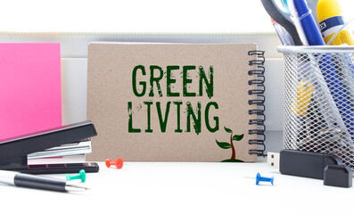 On a white-green surface, a piece of paper, a pen and a notepad with the text - Green Living.