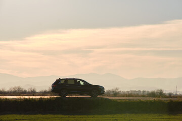 Naklejka premium Car driving fast on intercity road at sunset. Highway traffic in evening
