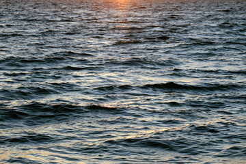 Dramatic bright red sky at ocean sunset, soft evening clouds over sea dark water