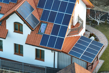 Fototapeta premium Private home roof covered with solar photovoltaic panels for generating of clean ecological electric energy in suburban rural town area. Concept of autonomous house