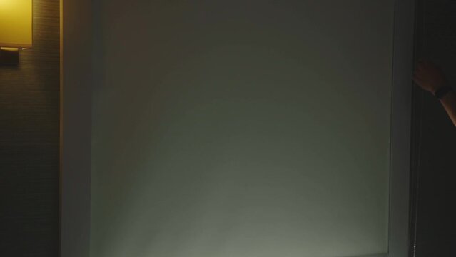 Person Closes The Roller Blinds Inside The Bedroom. Close Up