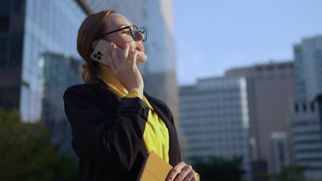 Satisfied Motivated Business Woman Finishes Phone Call Standing Outside Financial District Office Buildings And Looking Away Excited
