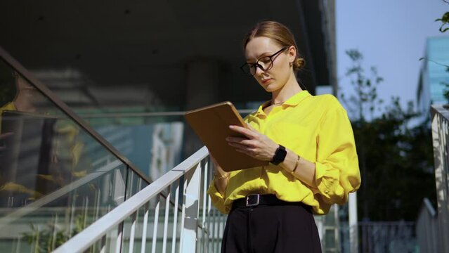 Real estate agent estimating price of office building standing using digital tablet PC outside on the stairs