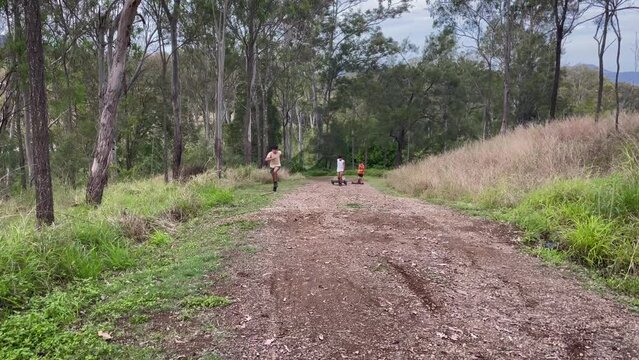 Active young boys walking up dirt track on hill with wooden go-carts. Australia