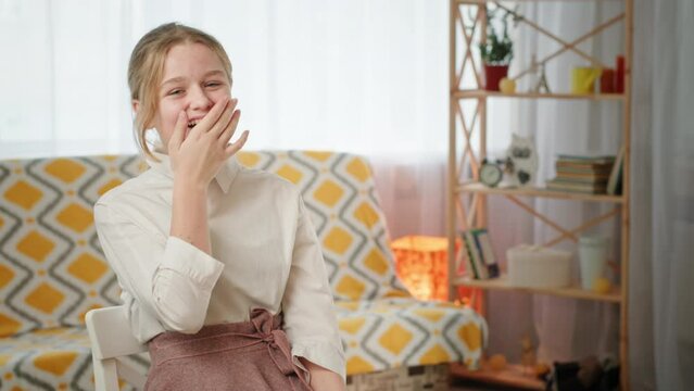 Blonde schoolgirl laughs tucking strand of hair behind ear