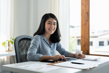 Portrait of attractive entrepreneur asian woman, business woman looking at camera while working for accounting finance with laptop computer.