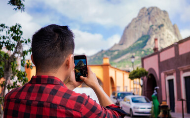 Unrecognizable young tourist taking pictures of the Peña de Bernal. Concept of tourism