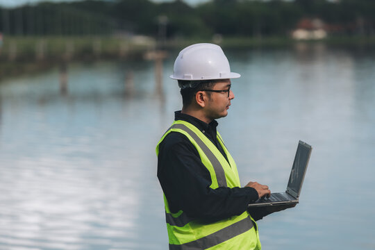 World environment day concept ,Thai Asian 
 man engineering working with a tablet laptop at sewage treatment plant, engineer controlling the quality of water , aerated activated sludge tank