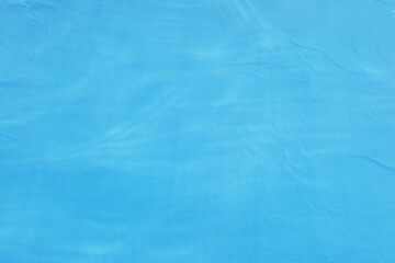 Defocus blurred transparent blue colored clear calm water surface texture with splash, bubble. Shining blue water ripple background. Surface of water in swimming pool. Blue bubble water shining.