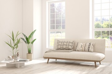 Fototapeta premium White living room with sofa and summer landscape in window. Scandinavian interior design. 3D illustration