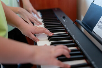 Midi keyboard or electronic piano and children's hands playing. Music education for a child in a music school. Individual music lessons with a teacher for school children. Selective focus