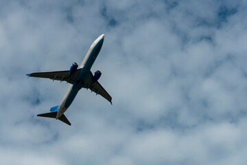 A white blue passenger plane with two engines against a cloudy sky.