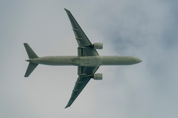 A white passenger plane with two engines against a cloudy sky.
