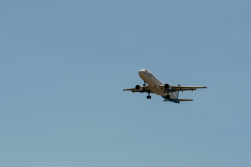 Aircraft in white blue coloring against the blue sky.