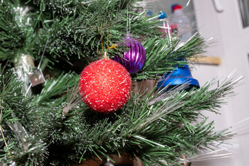 Christmas toys on the branches of a green Christmas tree.