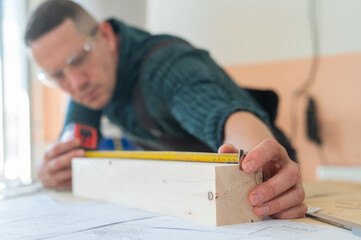 Fototapeta na wymiar Carpenter measures wooden planks in the workshop.