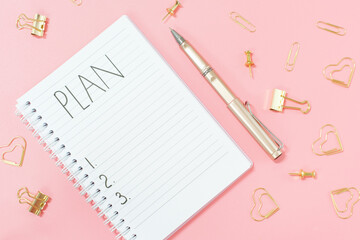 Inscription plan in blank notepad and stationery on pink background copy space.