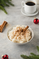  Scandinavian rice porridge with cinnamon in a bowl surrounded by Christmas balls. Breakfast on Christmas Eve.