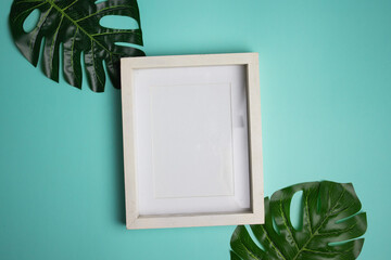 White wooden frame with green leaves over the mint table. 