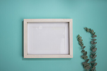 White wooden frame with green leaves over the mint background. 