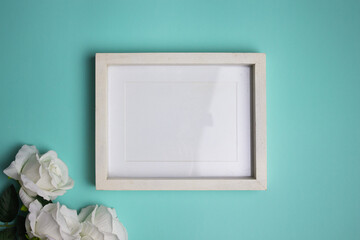 White wooden frame with white roses over the mint background. 