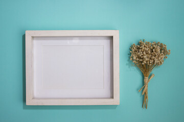 White wooden frame with white flowers over the mint background. 