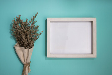 White wooden frame with flower leave over the mint background. 