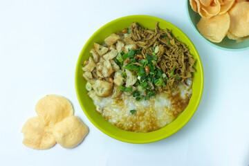 Bubur ayam Bandung or Chicken Porridge, Indonesian traditional food consist of white rice porridge, shredded chicken, cakwe, fried soybean, crackers, leek and egg. Selective focus.