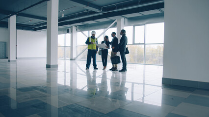 Business team are talking and looking around modern glass wall building standing inside discussing...