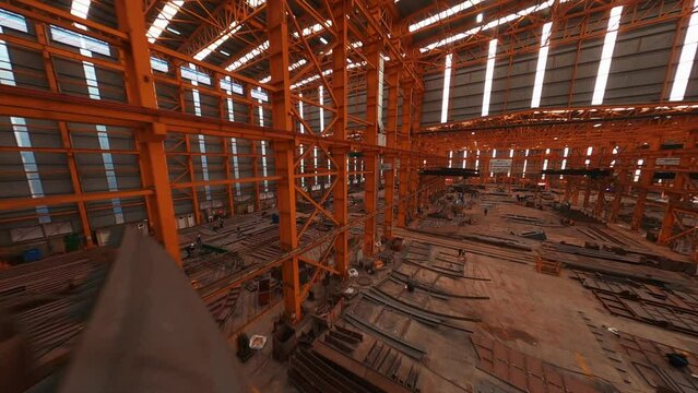 Shipbuilding industry. Inside the workshop of shipyard. The place of assembly of the hulls of ships. 4K. aerial view. FPV drone.