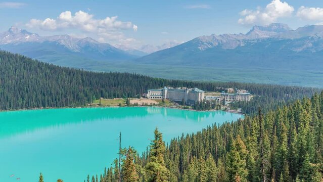 4K time-lapse UHD video of beautiful panoramic view of Lake Louise, a glacier mountain lake in Banff National Park, and Fairmont Chateau Hotel from a side view on a sunny summer day, Alberta, Canada