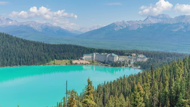 4K time-lapse UHD video of beautiful panoramic view of Lake Louise, a glacier mountain lake in Banff National Park, and Fairmont Chateau Hotel from a side view on a sunny summer day, Alberta, Canada