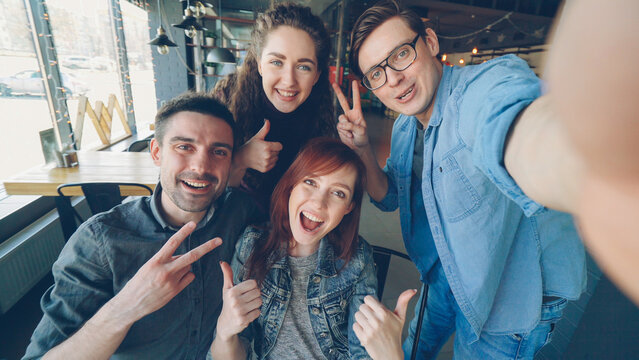 Point of view shot of cheerful friends taking selfie in pizzahouse posing and smiling, laughing and gesturing together. Friendship and happy young people concept.
