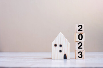 2023 Happy New Year with house model on table wooden background. Banking, real estate, investment, financial, savings and New Year Resolution concepts