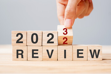 hand flipping block 2022 to 2023 REVIEW text on table. Resolution, idea, goal, motivation, reboot, business and New Year holiday concepts