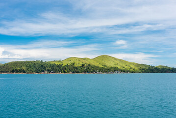 Lapinig Island, the main island of the town of President Carlos P. Garcia, Bohol. Small rolling hills covered by grasses jut out from the blue glassy ocean.