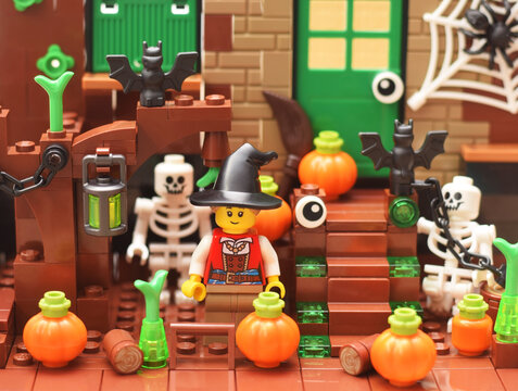Lego minifigure happy cute halloween witch with pumpkin near a house.  Editorial illustrative image of holiday.