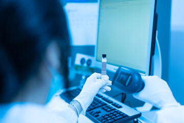 Woman scientist hand holding test tube barcode and scanner for automatic analysis machine in laboratory.Biologist working in modern laboratory with technological equipment.