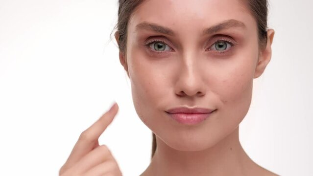 Close up. Concept for fresh moisturized elasticity skin. Portrait of adorable young Brunette woman massaging and touching her face after applying cream. Natural healthy face. slow motion.