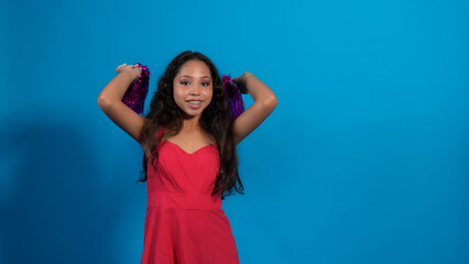 Niña en fondo azul, haciendo poses con pompones, Vestido rojo, porrista.
